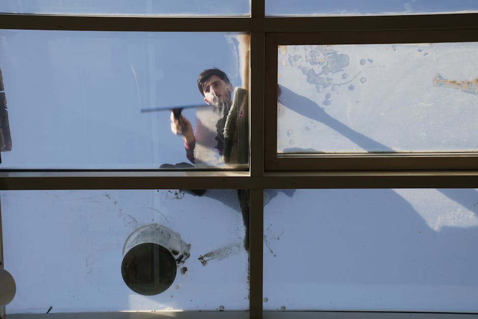 fensterreinigung - A male window cleaner washing the exterior glass roof from above with a tool during daylight.