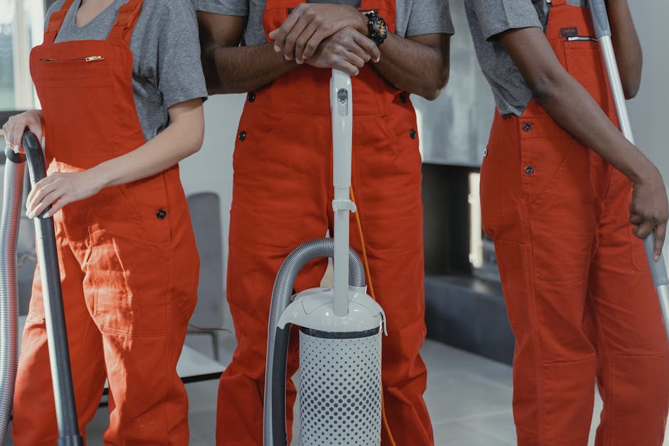 industrial cleaning services - Three workers in red coveralls with cleaning tools in a room.