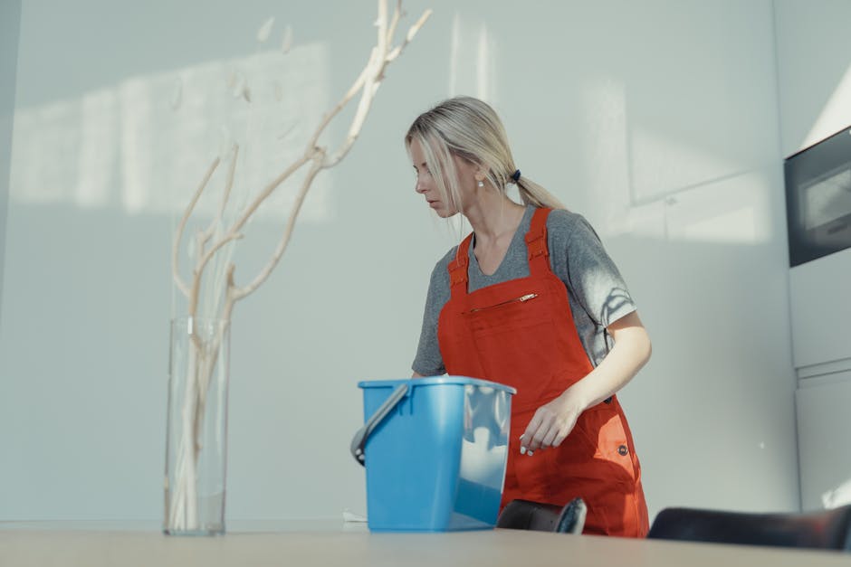 cleaning mini job near me - A woman in a red uniform cleans indoors with a blue bucket, ensuring a spotless environment.
