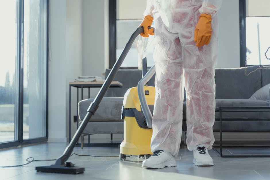 haushalt reinigen - A cleaner in protective coveralls and gloves vacuuming a modern living room.