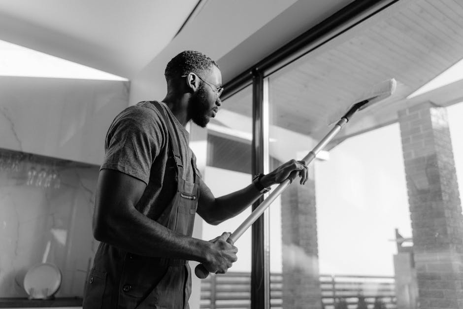 reinigungs service - A professional cleaner wiping large glass panels with precision inside a modern building.